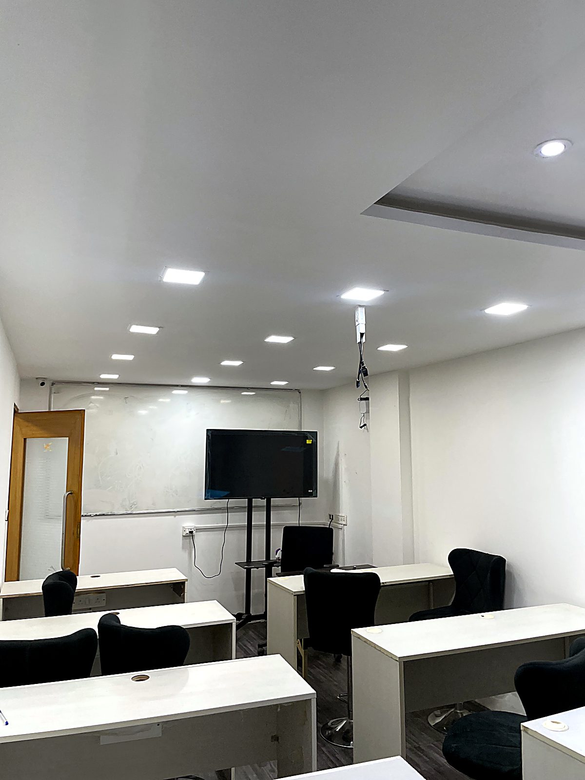 Capsley office workspace with desks, monitors and a presentation screen